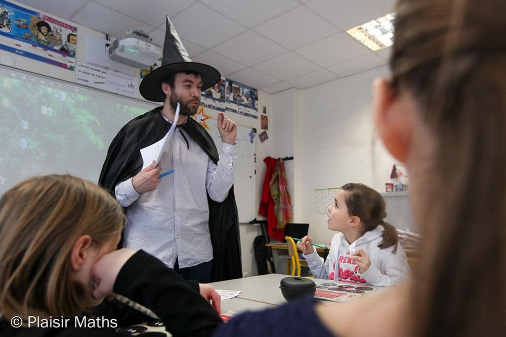 Animateur en costume de sorcier menant une séance de l'Atelier des Potions dans une classe
